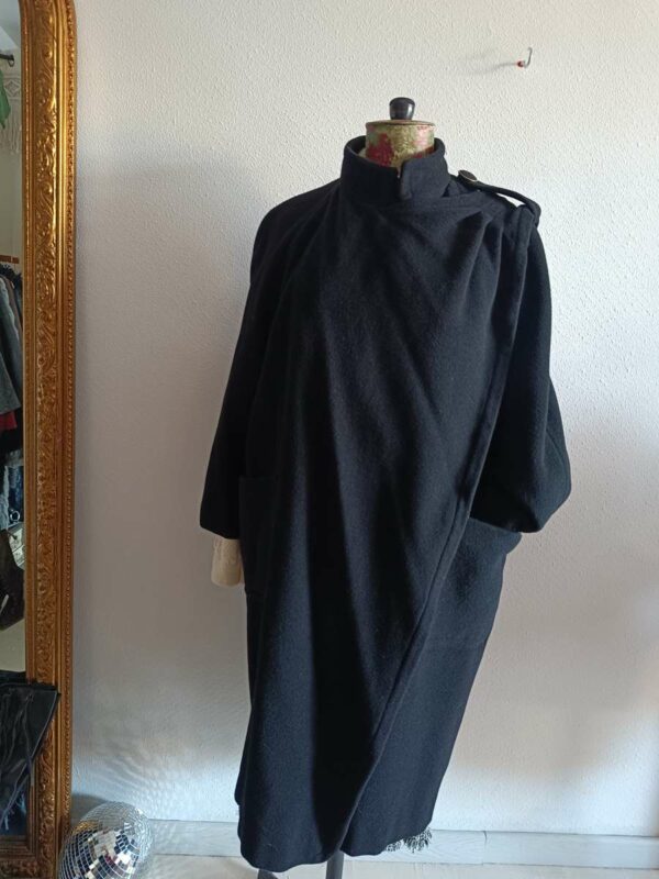 Magnifique manteau long noir de style vintage, doté d’une écharpe intégrée pour une allure élégante et structurée. Une pièce intemporelle, chic et facile à porter, idéale pour la saison automne/hiver.