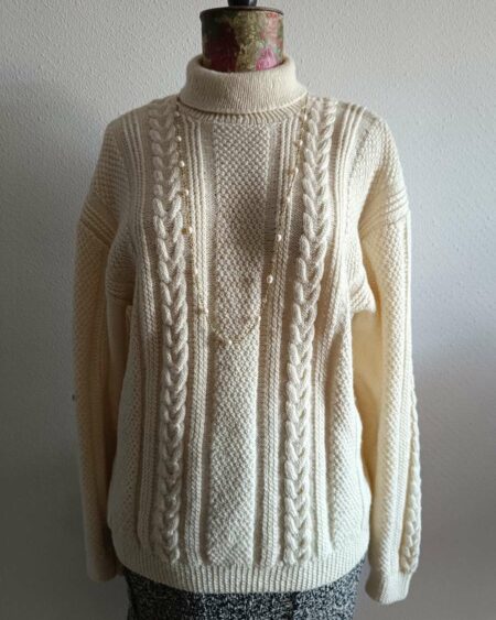 Superbe maille torsadée vintage en laine, au style intemporel et chaleureux. Son jeu de torsades verticales et son col légèrement montant en font une pièce élégante et confortable, idéale pour la saison automne/hiver.