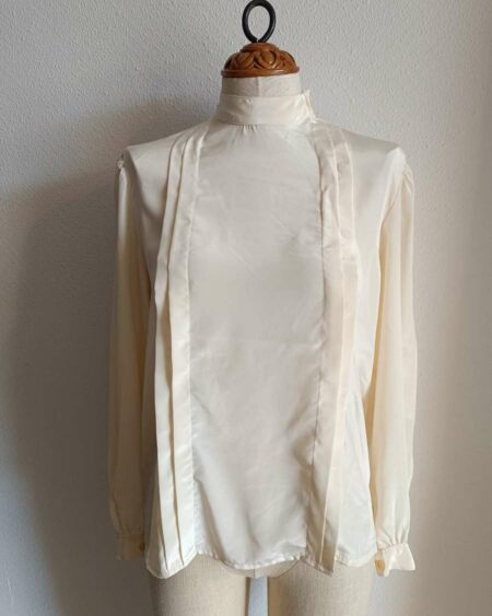 Description Chemisier vintage au style années 80, élégant et intemporel. Sa coupe fluide, son col montant discret et ses lignes verticales apportent une allure chic et soignée, idéale aussi bien pour une tenue de travail que pour un look plus rétro assumé. Fabriqué en France, ce chemisier en polyester offre une belle tenue et un tombé léger. Pièce en très bon état, soigneusement sélectionnée.