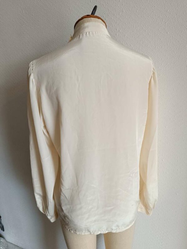 Description Chemisier vintage au style années 80, élégant et intemporel. Sa coupe fluide, son col montant discret et ses lignes verticales apportent une allure chic et soignée, idéale aussi bien pour une tenue de travail que pour un look plus rétro assumé. Fabriqué en France, ce chemisier en polyester offre une belle tenue et un tombé léger. Pièce en très bon état, soigneusement sélectionnée.