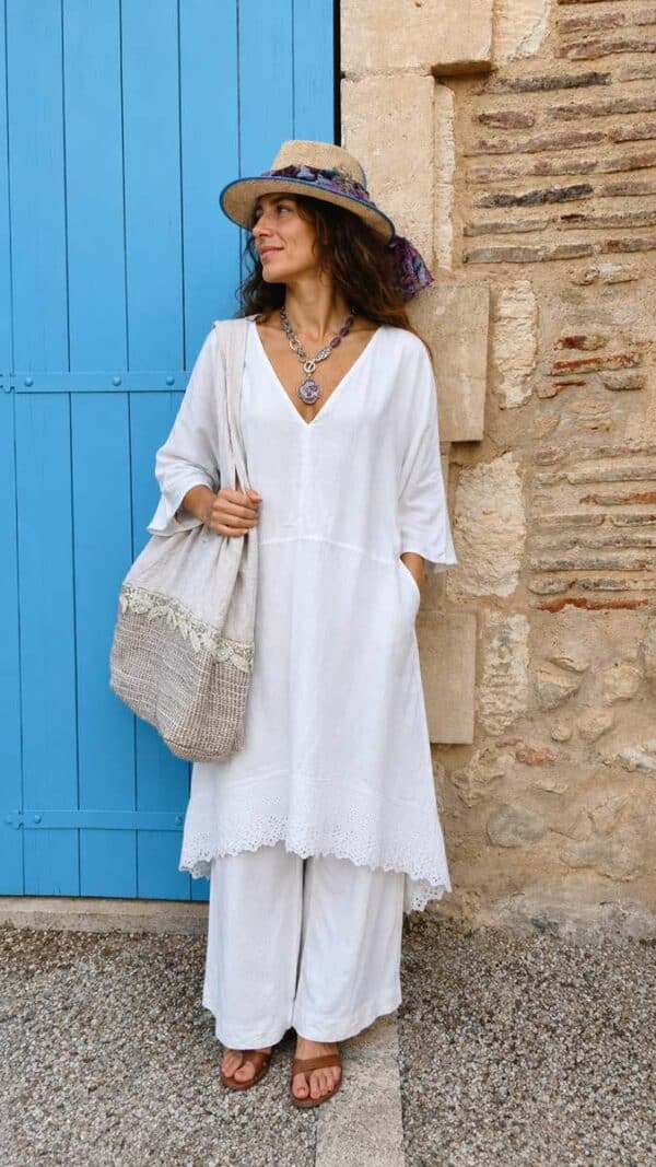Kaftan Upcyclé « Rivage Blanc » – Taille Unique Confectionné à partir d'un drap ancien soigneusement sélectionné, ce kaftan de la collection Les Héritières incarne toute la douceur des étés méditerranéens. Sa coupe ample et aérienne accompagne naturellement les mouvements tout en offrant un confort exceptionnel. Son encolure en V met délicatement le port de tête en valeur tandis que ses poches discrètes renforcent son esprit pratique et décontracté. Le bas du vêtement est sublimé par une magnifique broderie anglaise ancienne qui apporte relief, finesse et élégance à cette pièce intemporelle. Porté avec un pantalon blanc en coton ou en lin, il compose une silhouette lumineuse inspirée de la French Riviera, entre simplicité raffinée et charme bohème. Chaque modèle est réalisé en exemplaire unique dans notre atelier à partir de textiles anciens revalorisés.